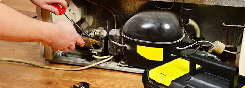 Refrigerator repair technician fixing the compressor and wiring in Spring Valley, CA