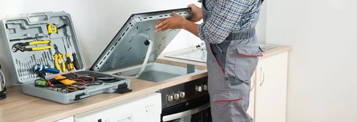 Cooktop repair technician lifting a built-in stovetop for service in Chula Vista, CA
