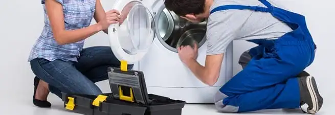 Washer repair technician inspecting a front-load washing machine with tools in Chula Vista, CA