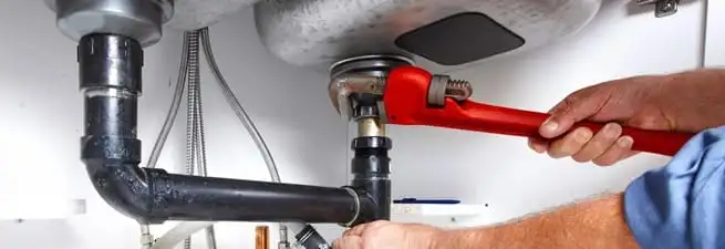 Garbage disposal repair technician tightening the sink drain and disposal connection in Chula Vista, CA