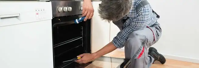 Oven repair technician inspecting and servicing an electric oven in Chula Vista, CA
