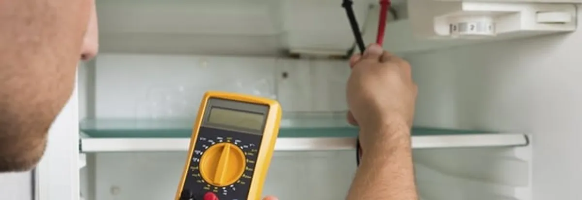 Refrigerator repair technician testing electrical components with a multimeter in Chula Vista, CA