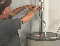 Water heater repair technician tightening supply line connections in Chula Vista, CA