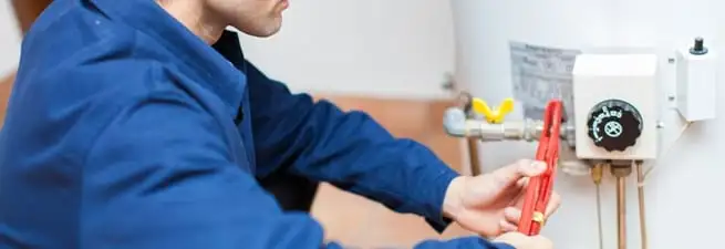Water heater repair technician adjusting the temperature control and gas valve in Chula Vista, CA